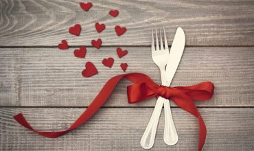 couverts attachés par un ruban rouge pour une table de Saint Valentin