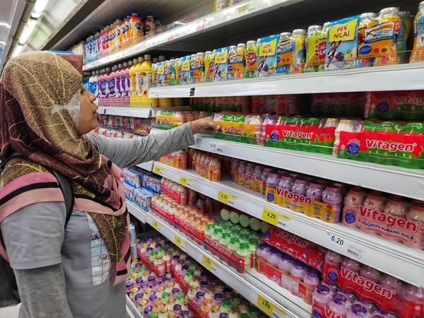 femme musulmane qui fait ses courses au rayon des boissons halal d'un supermarché
