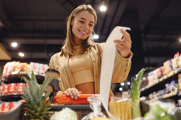 jeune femme qui regarde son ticket de caisse en souriant